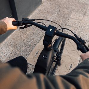 The POV of a cyclist riding their AnyTour E+ electric city bike looking down at their handlebars.