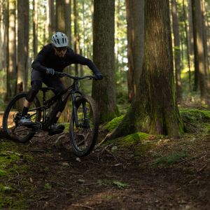 A mountain bike skids into the corner of a banked trail in the forest.