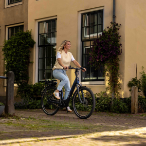 A female cyclist rides down a pedestrian path between apartments on a Giant Entour E+ city bike.