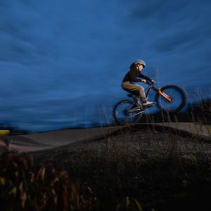 A young rider wheelies over a roller on a Giant STP 24 dirt jumper.