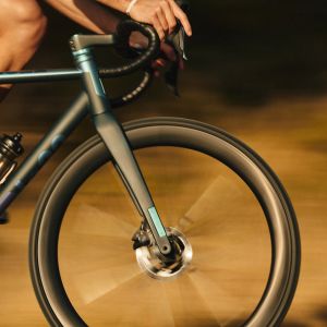 A close look at the front end of a road bike mounted with CADEX Aero Tires riding by.