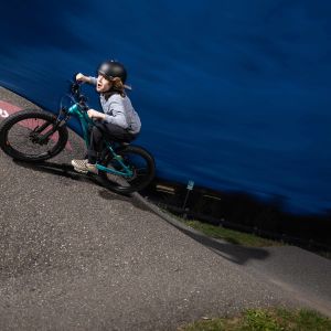 A young rider takes a huge berm at a bike park at speed on a Giant STP 20.