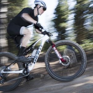 A mountain biker climbs at speed on their Giant Anthem Advanced SL with Giant XCR carbon wheels.