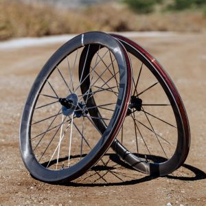A set of CADEX Max GXR carbon fiber gravel bike wheels are staged on a gravel road.