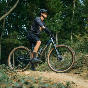 A mountain biker waits on he side of a trail on their Giant Talon E+.