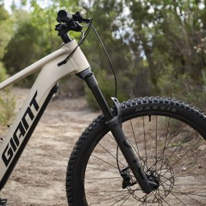 A close up look at the front end of the Giant Stance E+ trail bike out on a trail.