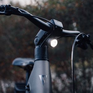 A close up look at the front light on the Giant AnyTour E+ city bike staged in the outdoors at dusk.