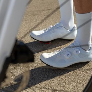 A cyclist stands next to their road bike in their Giant Surge road bike shoes.