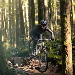 Woman riding down a trail in the mountain on Liv Embolden wearing all black.