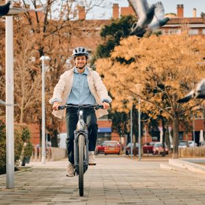Cyclist approaches riding a Giant Anytour E+ through a park.
