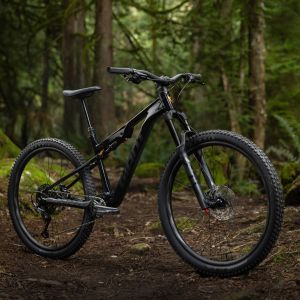 The Giant Stance full suspension trail bike posed at an angle in the forest.