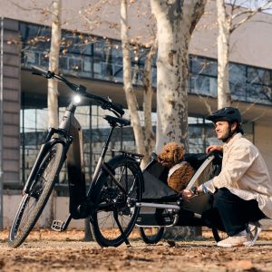 Cyclist loads a puppy into a bike trailer attached to his Giant Anytour E+.