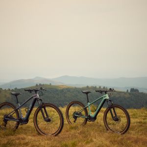 Two Liv Tempt E+ mountain bikes standing in a field.