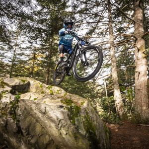 Enduro mountain biker jumping off big rock