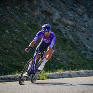 A Jayco Alula pro cyclist leans into a corner on their Propel Advanced SL road bike wearing Giant Surge Pro Road bike shoes.