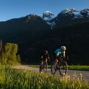 Two cyclists ride in single file on a dirt road in a scenic valley riding Giant Revolt Advanced SL gravel bikes.