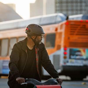 A cyclist cruises through the city checking for traffic while wearing a Giant Novo helmet.
