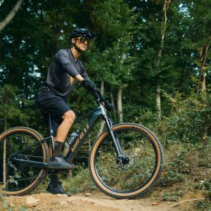 A mountain biker waiting on the side of a trail with their Giant Talon E+ hardtail mountain bike.