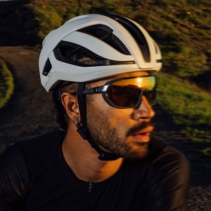 A close up look at a cyclists face while they observe the sunset off to their left wearing a Giant Rev Pro helmet.