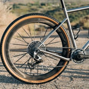 A close up look at the rear CADEX Max GXR gravel wheel fitted on a titanium gravel bike on a dirt road.