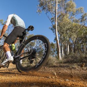 A gravel cyclist wearing Giant Charge Pro gravel/XC shoes, skids around a dirt corner on his Giant Revolt Advanced SL gravel bike.