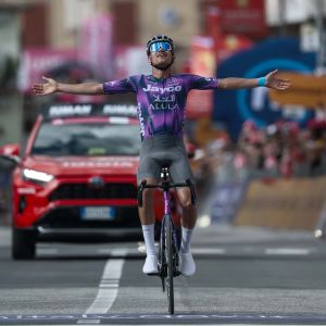 A pro rider from Jayco Alula rides across the finish line hands in the air in victory on a Giant Propel Advanced SL team bike.