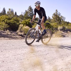 A gravel cyclist rides down a dirt road on their Giant Revolt Advanced SE.
