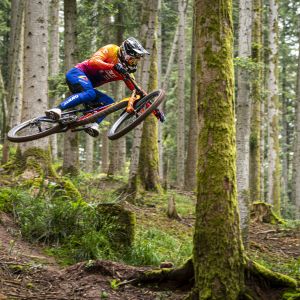 Downhill rider jumping on track in forest