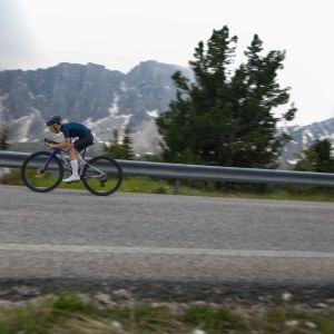 A youth road biker rides a Giant Seek with SLR40 1 650 wheels with snowy mountains in the background.