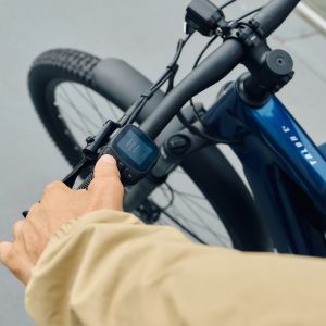 A cyclist thumbs the control unit on the handlebar of their Giant Talon E+ EX hardtail bike.