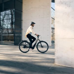 Cyclist rides Giant Anytour E+ between buildings.
