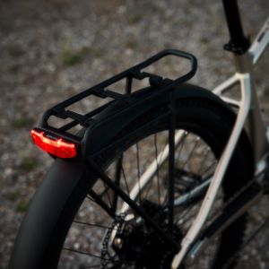 A rear view of the Liv Tempt E+ EX with the rear rack integrated tail light illuminated at dusk.