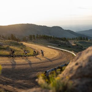 road bikers riding dirt road during sunset
