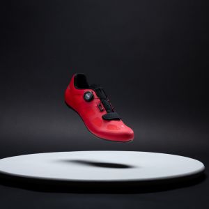 A look at the top of the Giant Surge 2 road shoe in the red colorway with a stylized studio background.