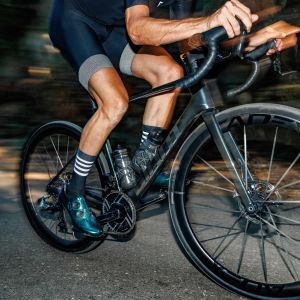 A cyclist riding a shaded tree lined road on a Giant Defy with Cadex Ultra 40 wheels.