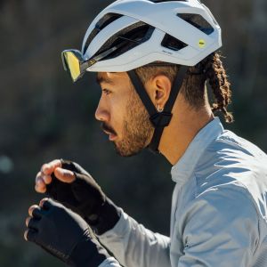 A cyclist wearing a Giant Rev Pro helmet finishes adjusting his sunglasses.