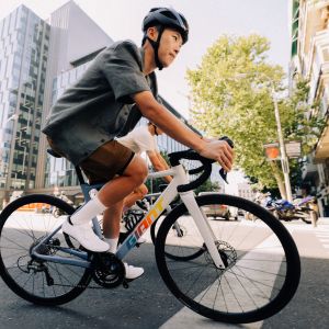 A side view of a few roadies on Giant Contend SL aluminum road bikes pedaling through city streets.