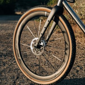 A close up look at the front CADEX Max GXR gravel wheel fitted on a titanium gravel bike on a dirt road.