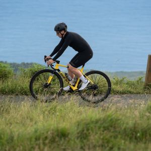 Action shot of a cyclist riding the Giant TCR Advanced SL Legends Edition frame along a a mountain ridge above the ocean.