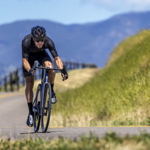 Cyclist rides up a mountain road on a Giant Defy E+ Elite.