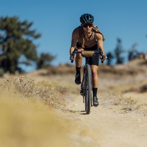 Woman riding the Devote down a gravel path.