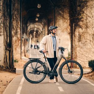 Cyclist poses with Giant Anytour E+ under large pillars adorned with ivy.  