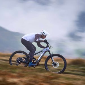 An enduro mountain biker flies down a mountain trail on a Giant Reign Advanced E+.