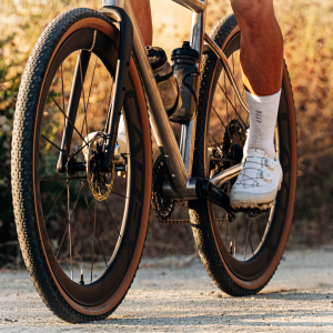 A rider  on a dirt road passes by on a gravel bike with CADEX Max GXR gravel wheels.