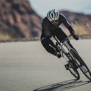 Road cyclist leans into a corner with Cadex Aero integrated handlebars.