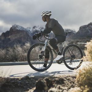 Road cyclist takes a rest to enjoy a snowy mountain backdrop.