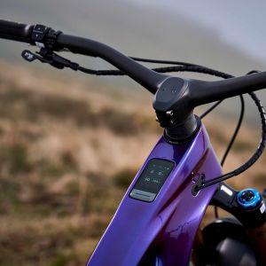 An angled rear drive-side overhead view of the Giant Reign Advanced E+ enduro bike cockpit and integrated computer with mountains in the background.