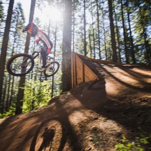 young cyclist jumping out of a berm on full suspension kids bike