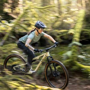 semi-blurred, woman riding through forest on Liv Embolden.