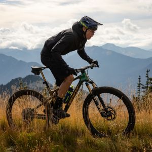 A cross country mountain biker rides a Giant Anthem X Advanced SL on a mountain ridge with a sunset in the background.